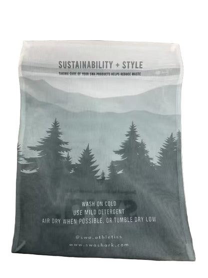 Fabric bag with sustainability and style text, tree design, and care instructions on a wooden surface.