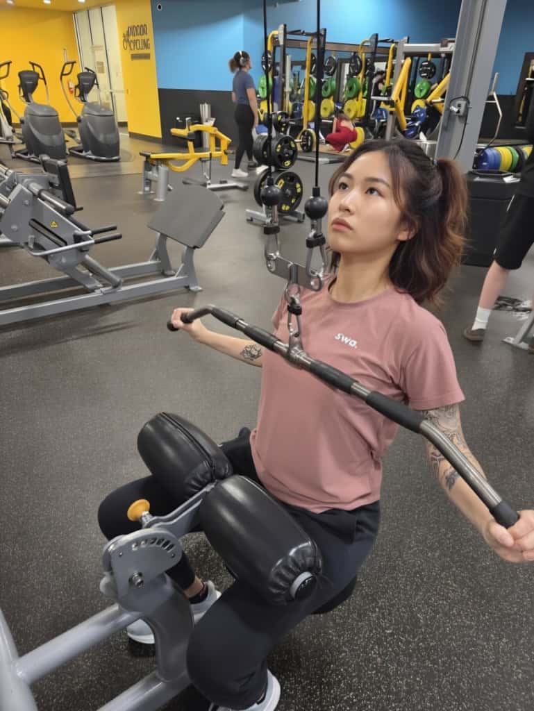 Woman wearing a salmon swa t-shirts, and exercising on a leg press machine in a gym