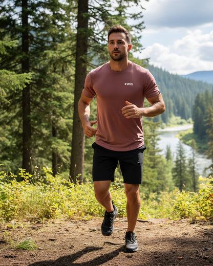 Man running wearing a salmon swa t shirt, on a trail in a forest with a river in the background